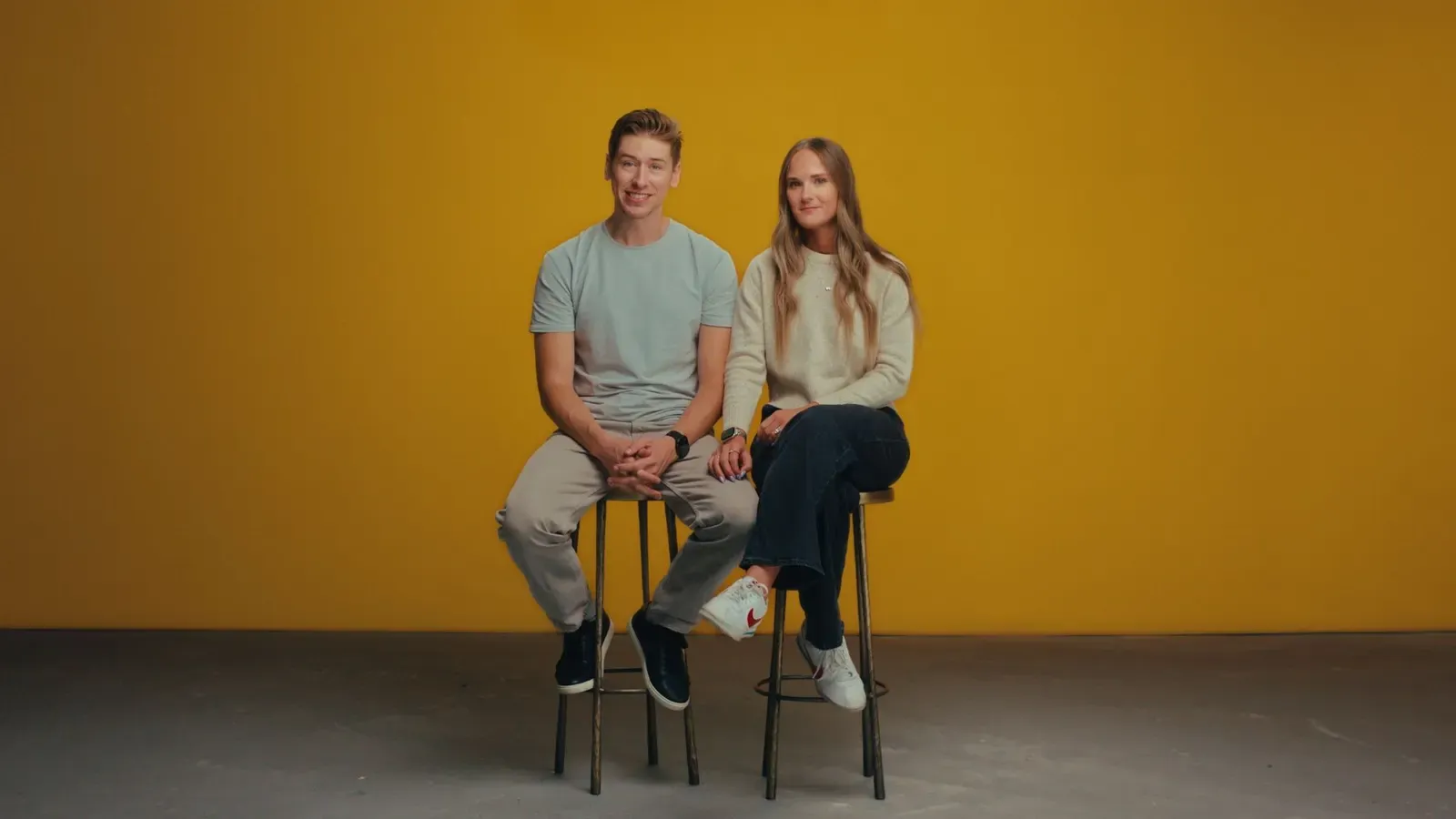 The Dotsons seated side by side on stools against a yellow backdrop